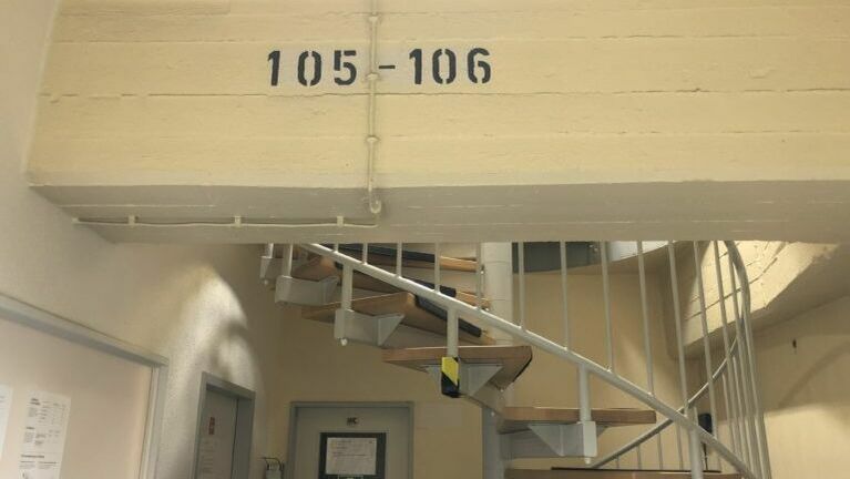 Treppenaufgang in einem Parkhaus. Auf der Wand steht die Nummer 105-106.
