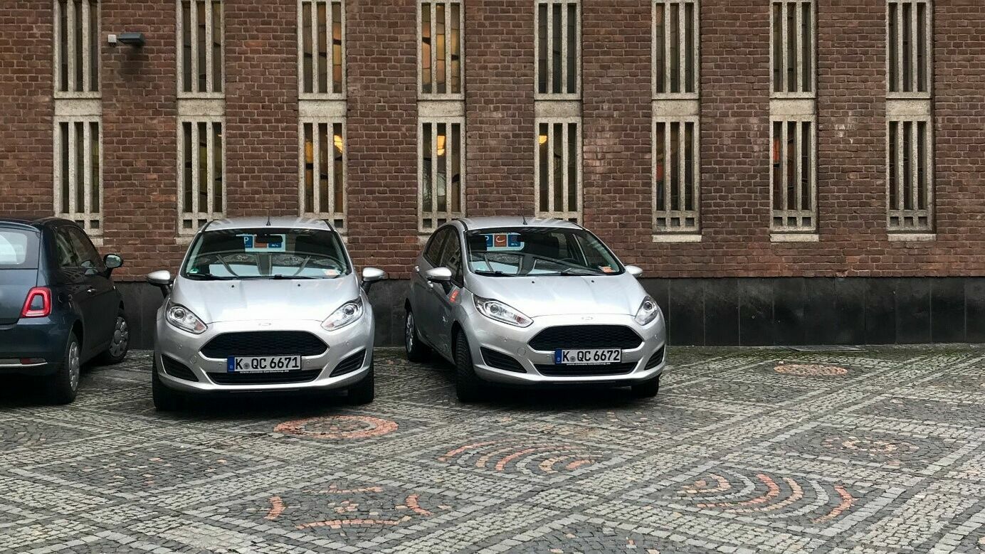Zwei cambio-Autos parken vor einem Gebäude.