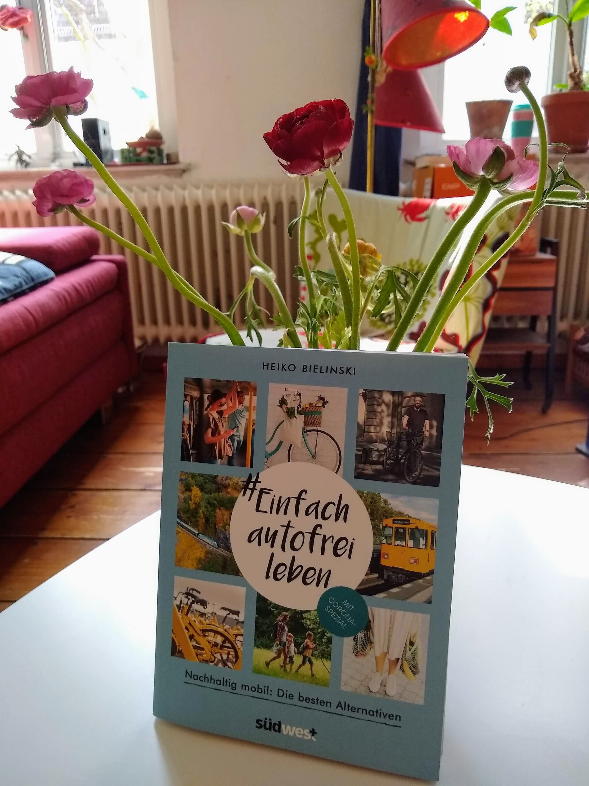 Das Buch von Heiko Bielinski an einer Vase mit Blumen gelehnt auf einem Tisch im Wohnzimmer.