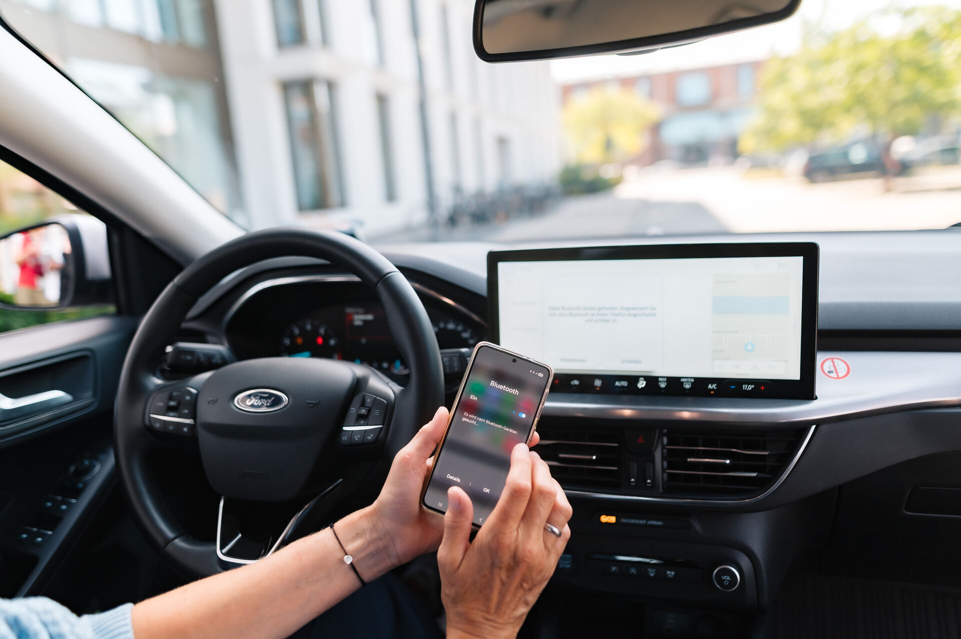 Eine Person koppelt ihr Smartphone per Bluetooth mit dem Auto.