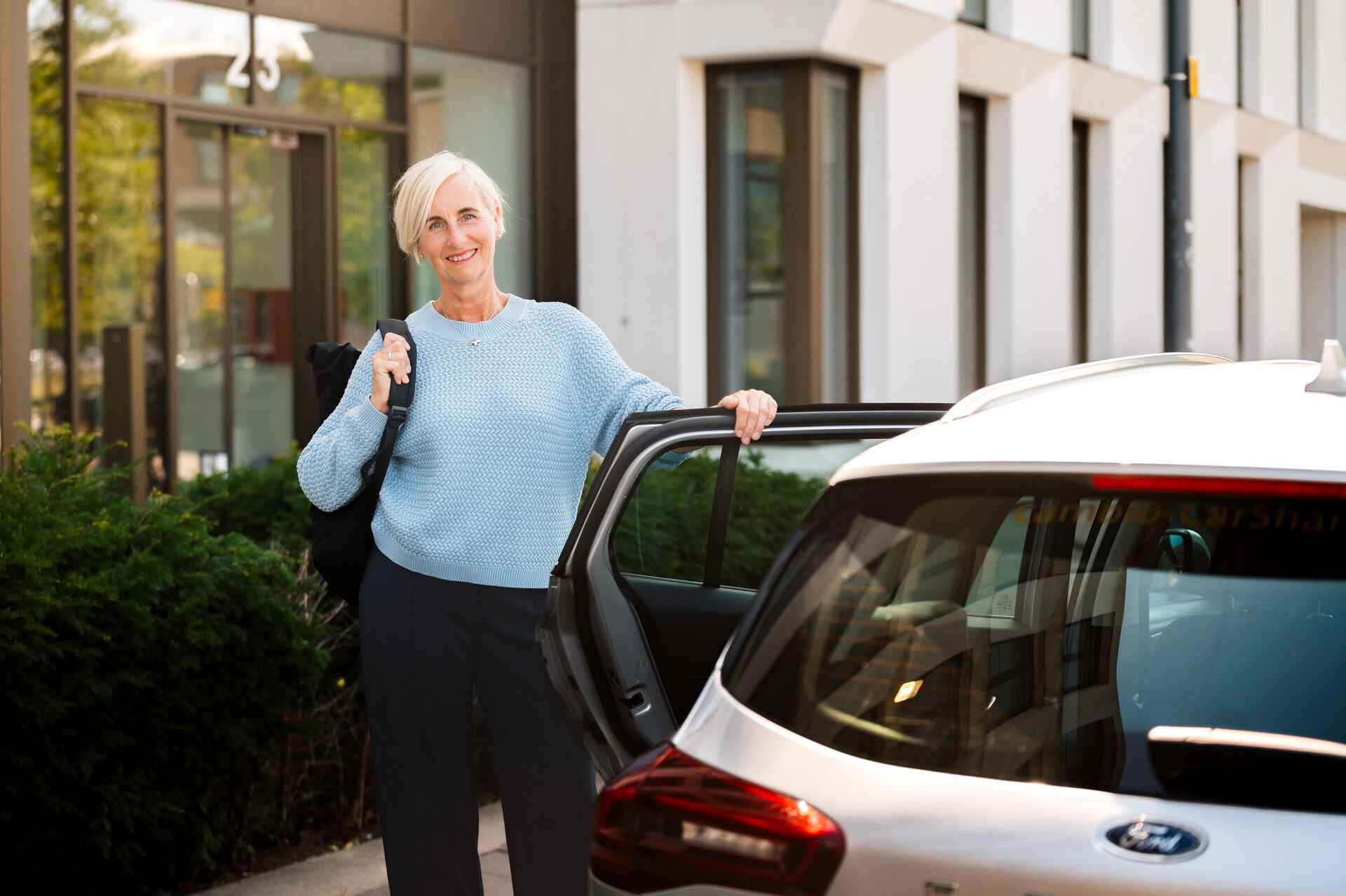 Eine Frau steht an einem CarSharing-Auto.