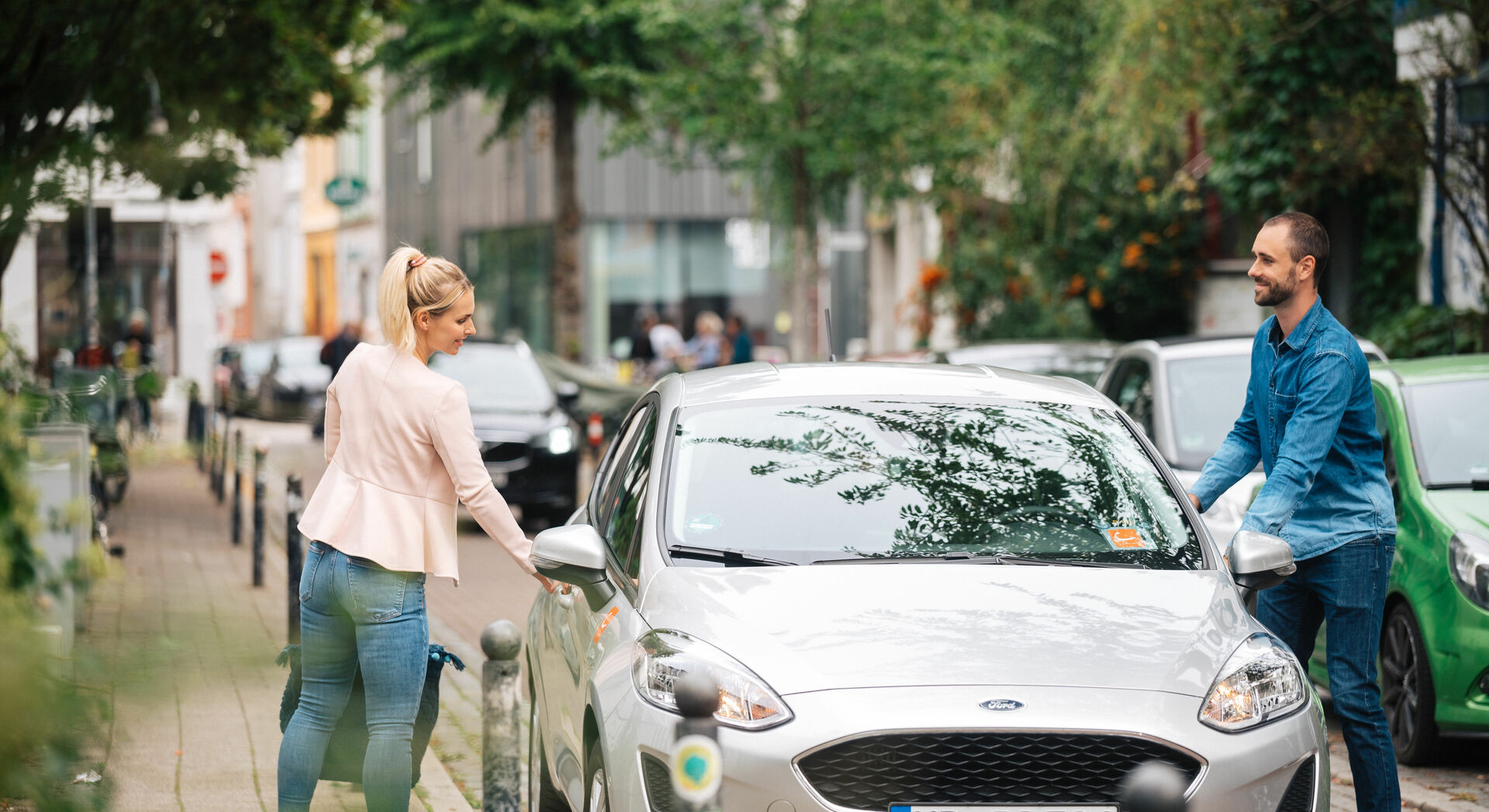 Eine Frau und ein Mann steigen in ein cambio-Auto ein.