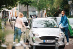 Eine Frau und ein Mann steigen in ein cambio-Auto ein.