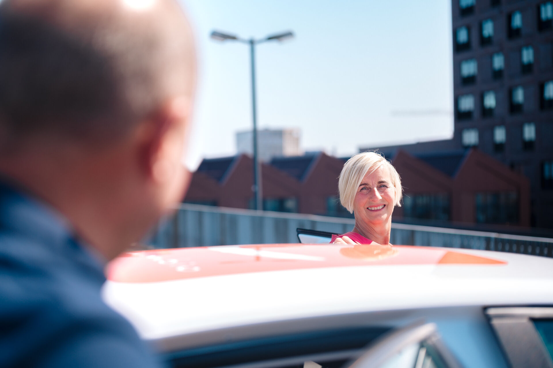 Eine Frau steigt in ein Auto ein und lächelt.