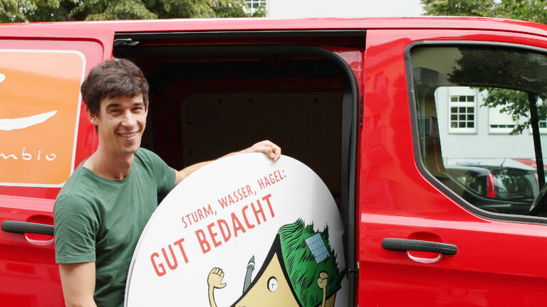 Mann lädt weißes Schild in rotes Auto