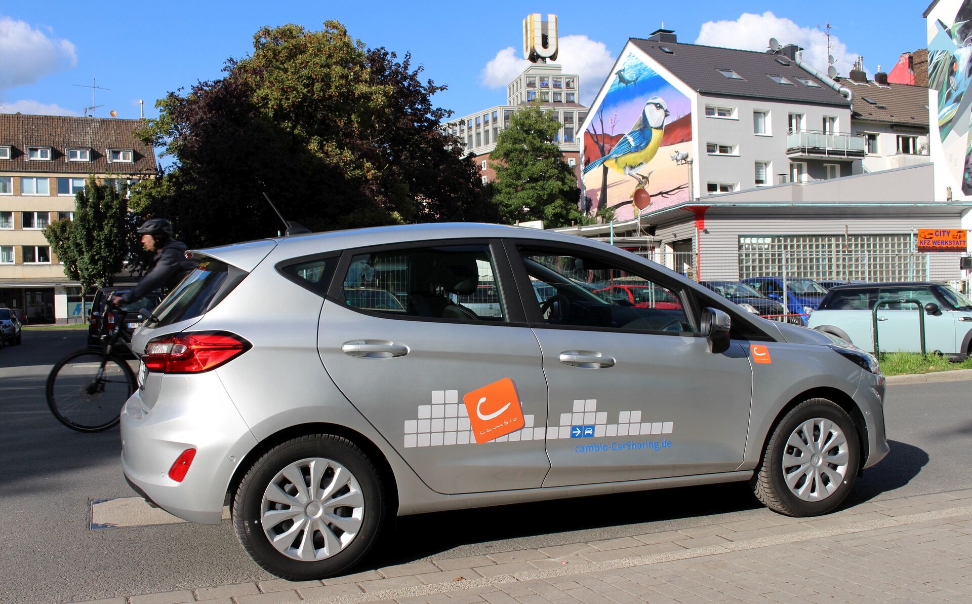 Silbernes Auto mit cambio-Aufdruck, im Hintergrund sieht man das Dortmunder U.