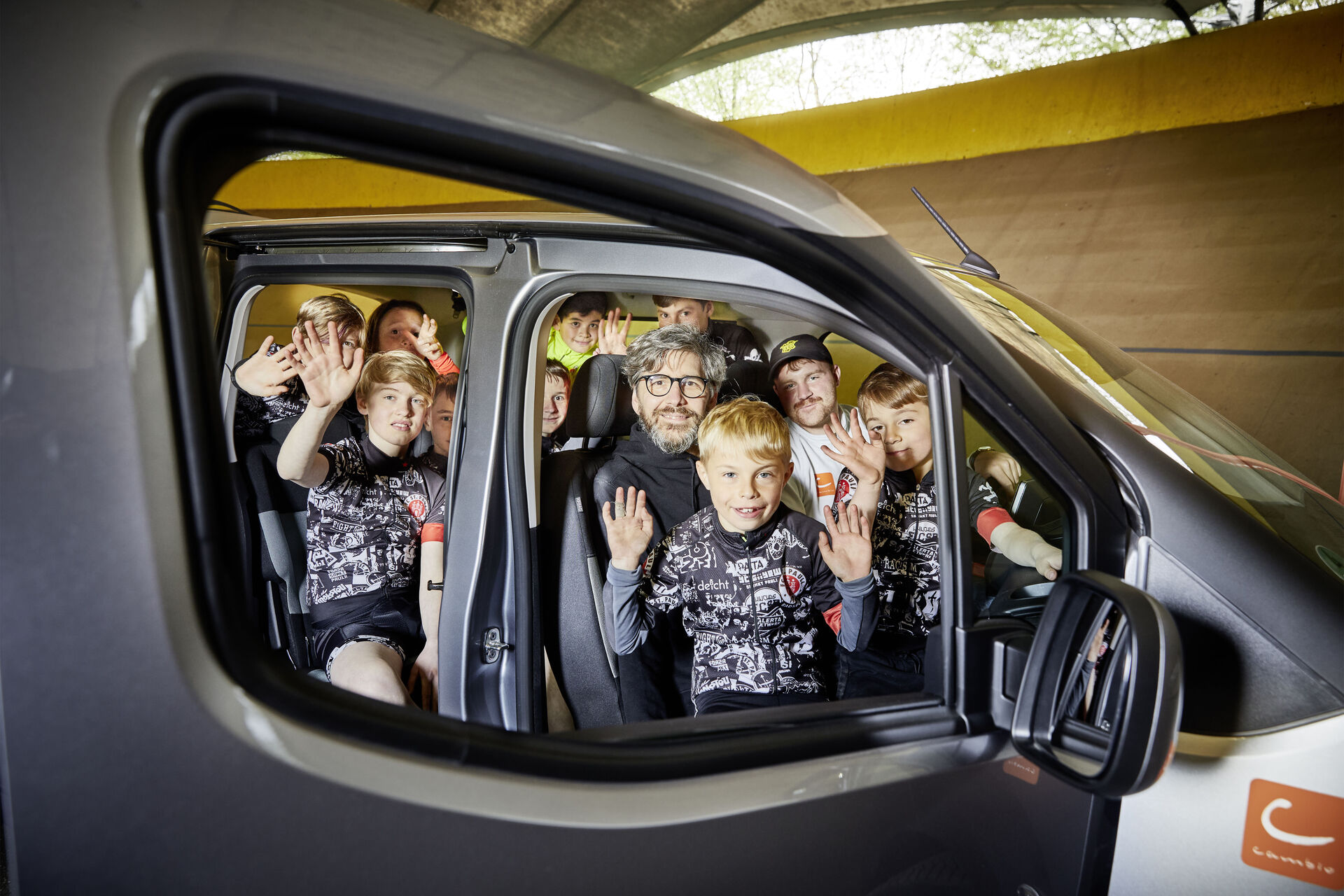 Eine Gruppe Kinder und Erwachsene sitzt in einem Auto.