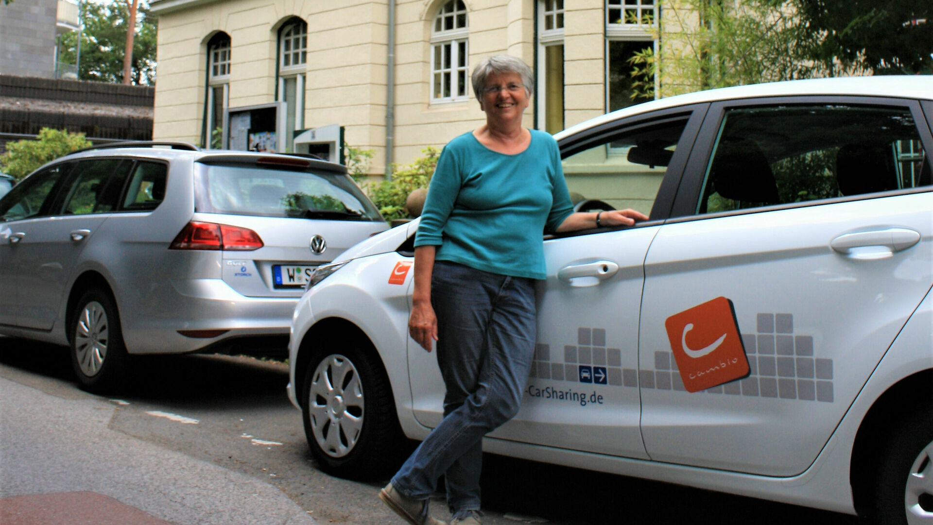 Eine Frau steht lächelnd vor einem Auto von cambio