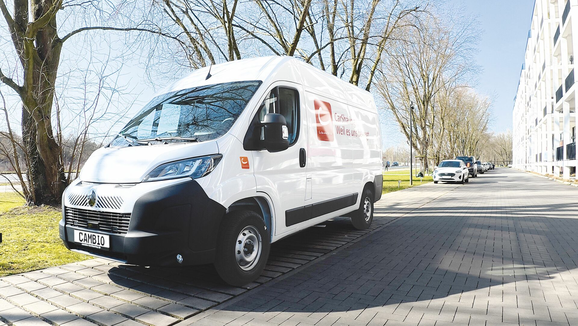 Ein weißer Transporter von cambio parkt am Straßenrand