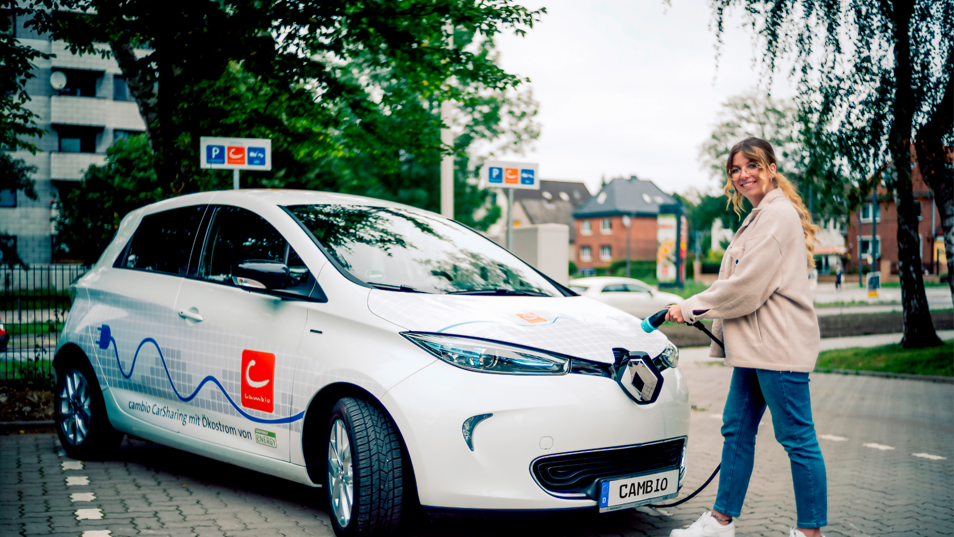 Frau lädt E-Auto an Station