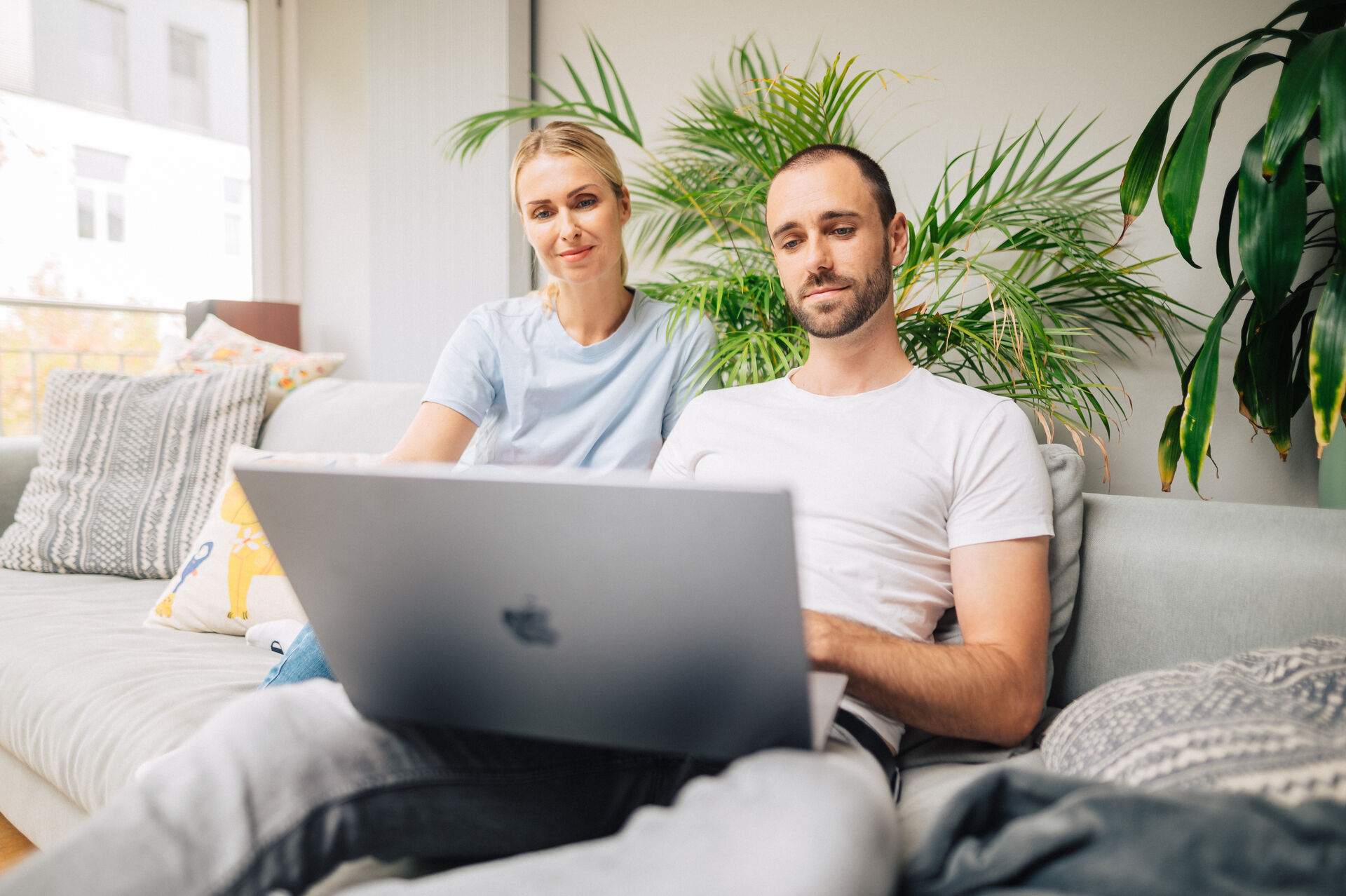Mann und Frau sitzen auf Sofa und schauen auf Laptop