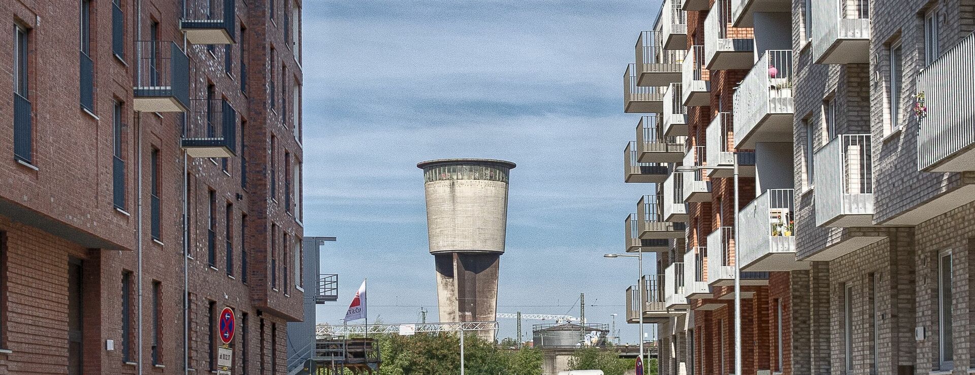 Blick auf einen Turm, rechts und links sieht man Wohnhäuser und viele Balkone