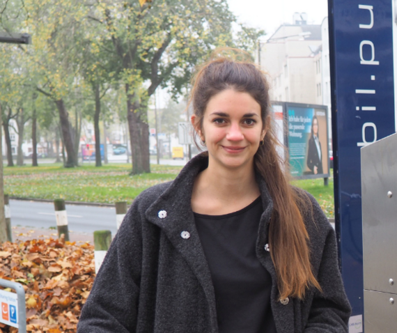 Junge Frau steht vor einem blauen Schild