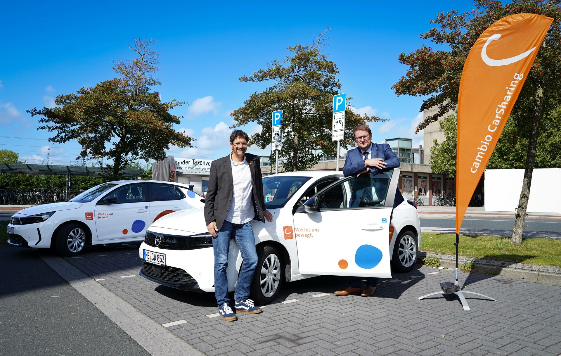 Fleming Erdwiens von cambio und Oberbürgermeister Tim Kruithoff stehen an einer CarSharing-Station in Emden