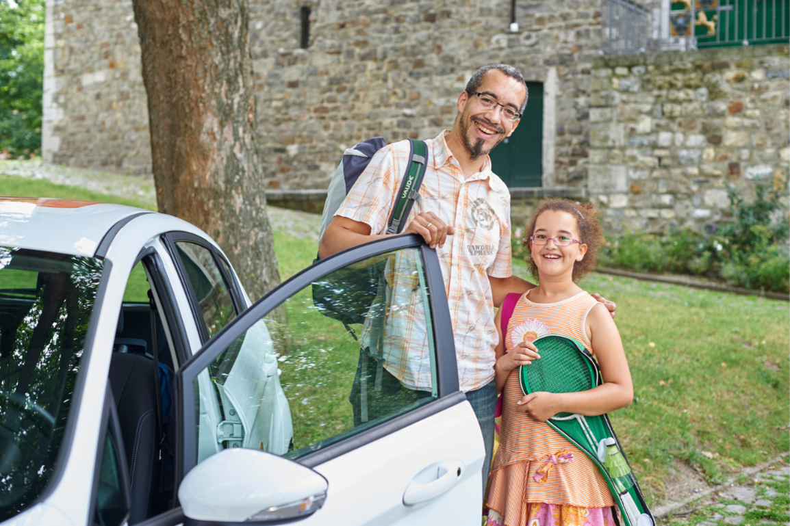 Vater und Kind in sommerlicher Kleidung neben cambio-Auto
