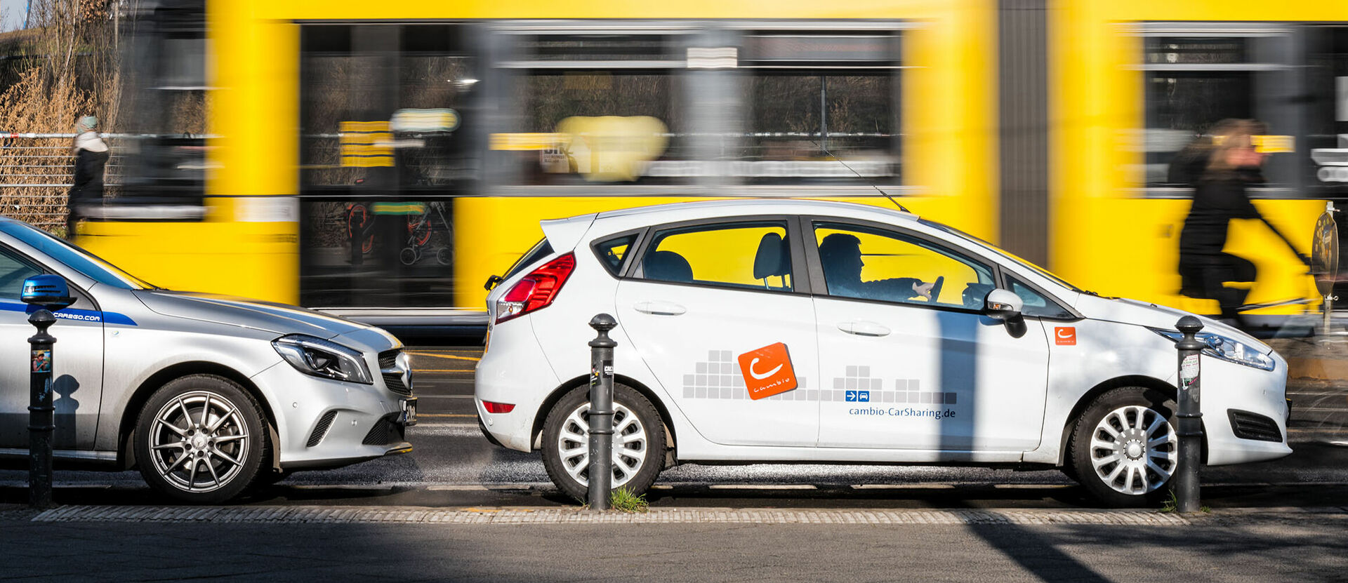 Im Vordergrund ein cambio-Auto aus Berlin, im Hintergrund die Strassenbahn.