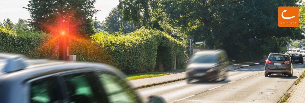 Ein rotes Auto wird von einer elektronischen Geschwindigkeitskontrolle geblitzt