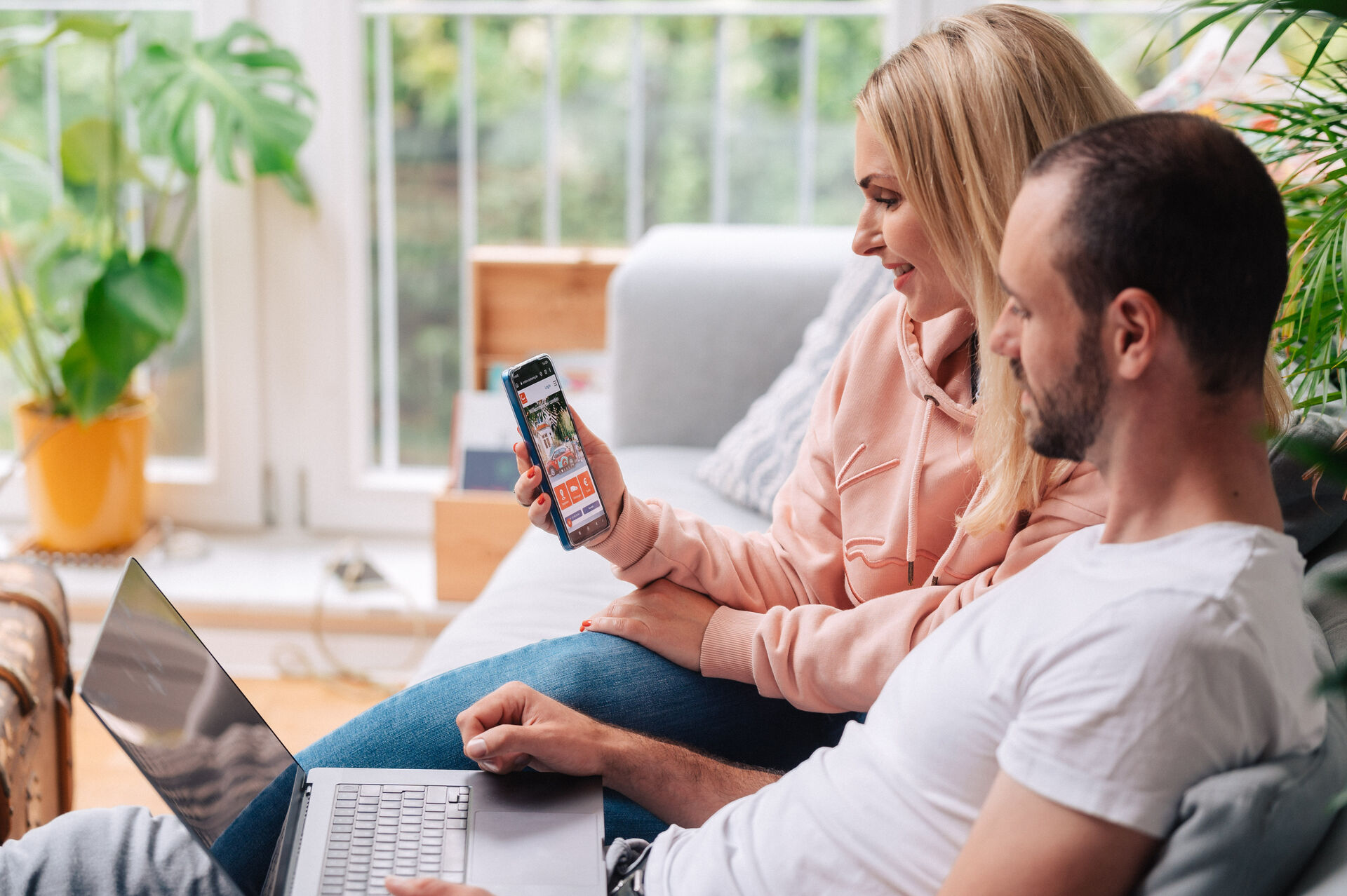 Mann und Frau sitzen auf Sofa und schauen auf Laptop