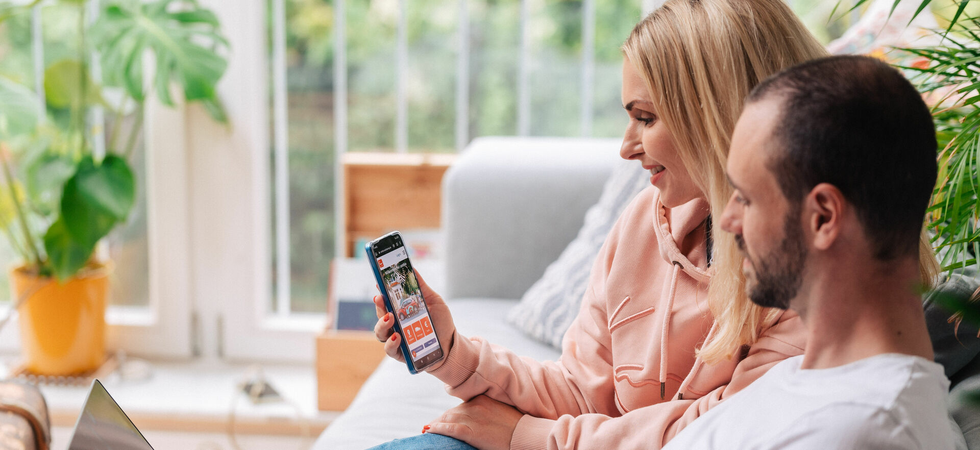 Mann und Frau sitzen auf Sofa und schauen auf Laptop