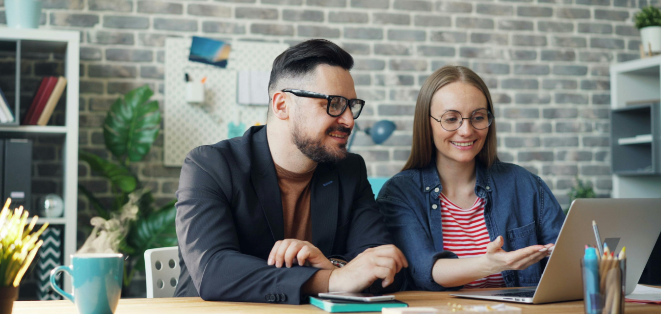 Eine Frau und ein Mann schauen gemeinsam auf einen Bildschirm.
