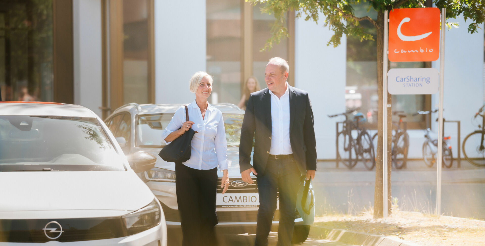 Eine Frau und ein Mann gehen an CarSharing-Autos vorbei.
