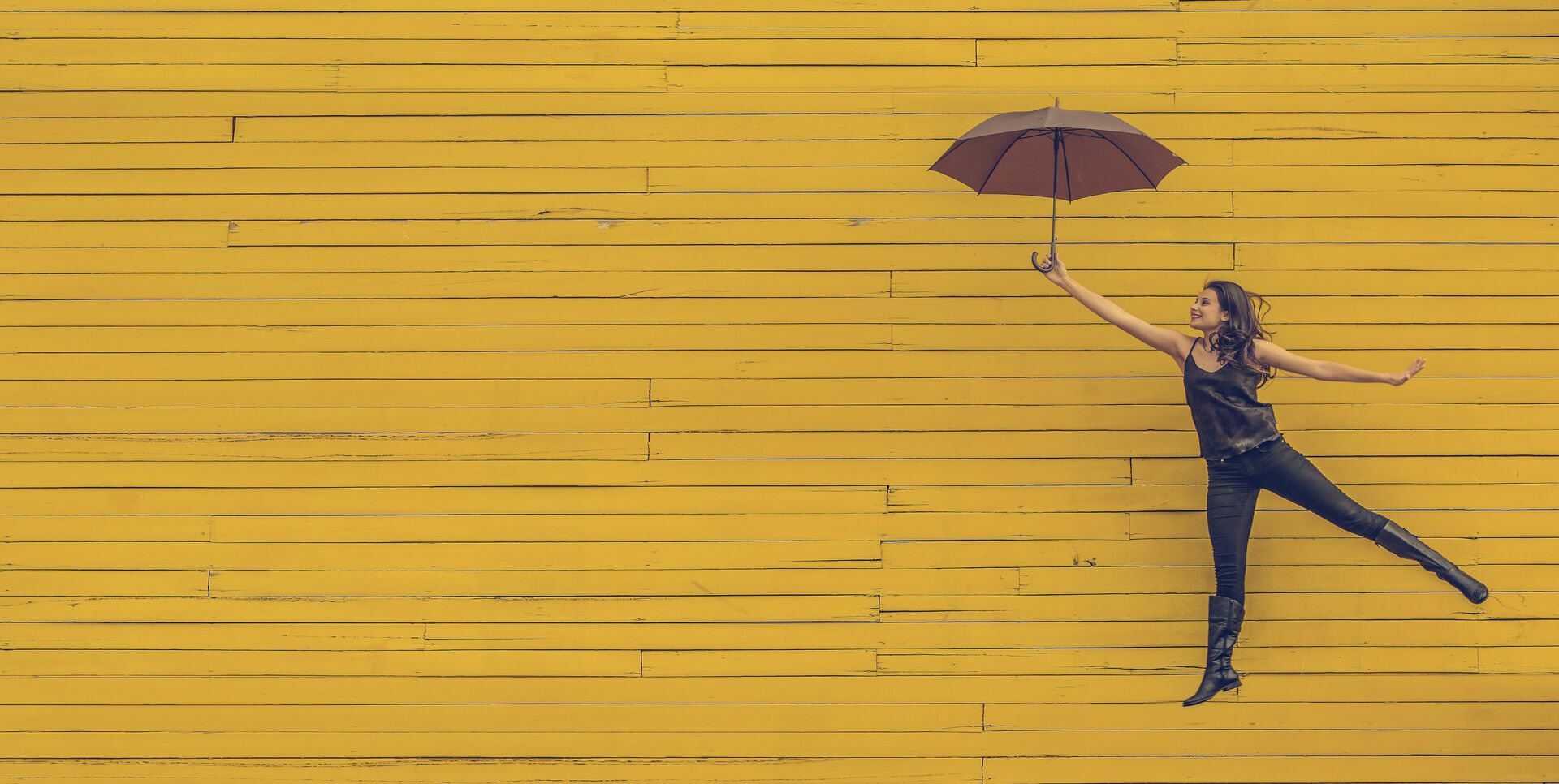 Frau mit Regenschirm vor gelbem Hintergrund
