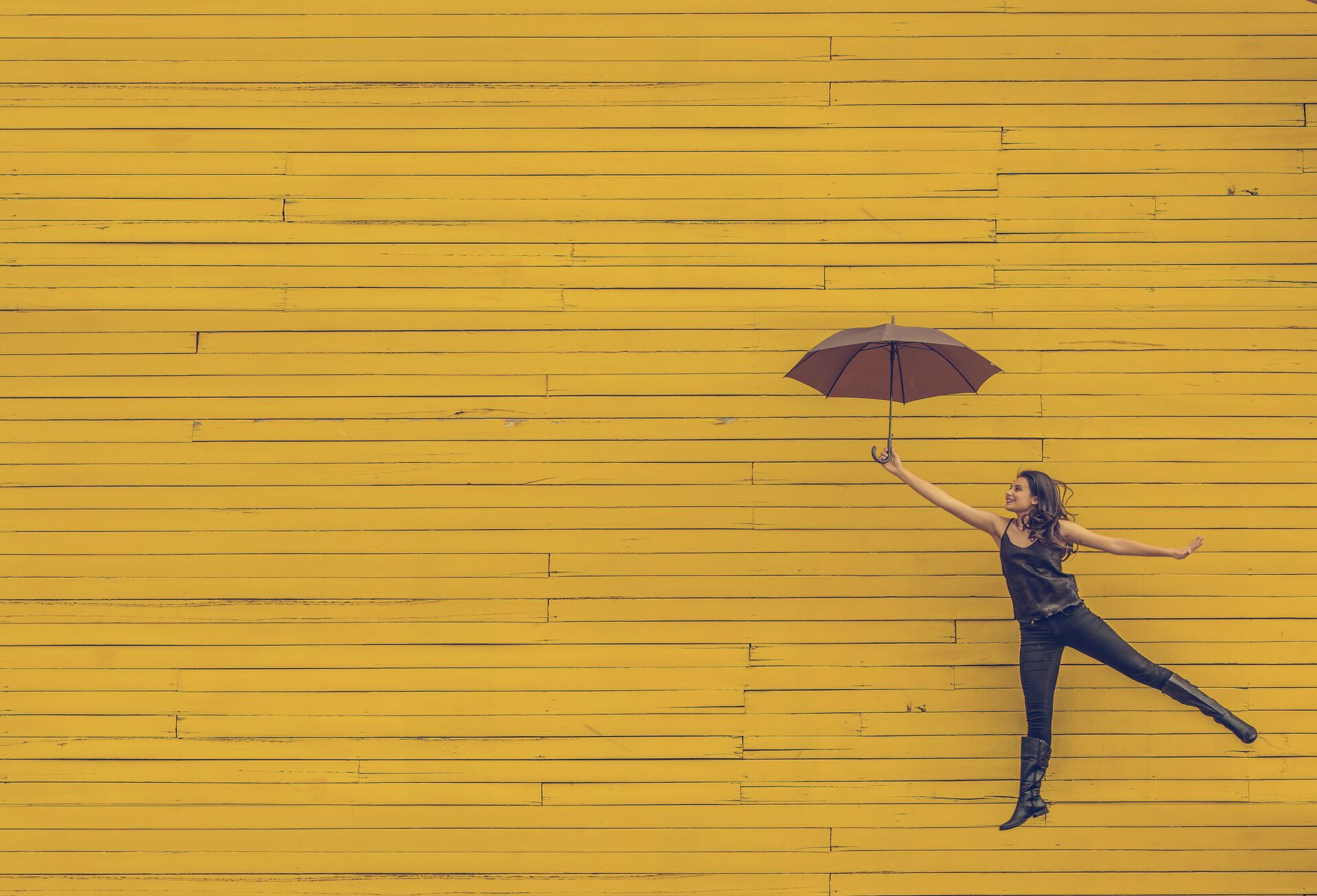 Frau mit Regenschirm vor gelbem Hintergrund