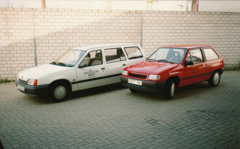 Zwei Autos nebeneinander. Ein Kombi in weiß, links und ein Zweitürer in rot, rechts. Beide Autos sind aus dem Jahr 1992.