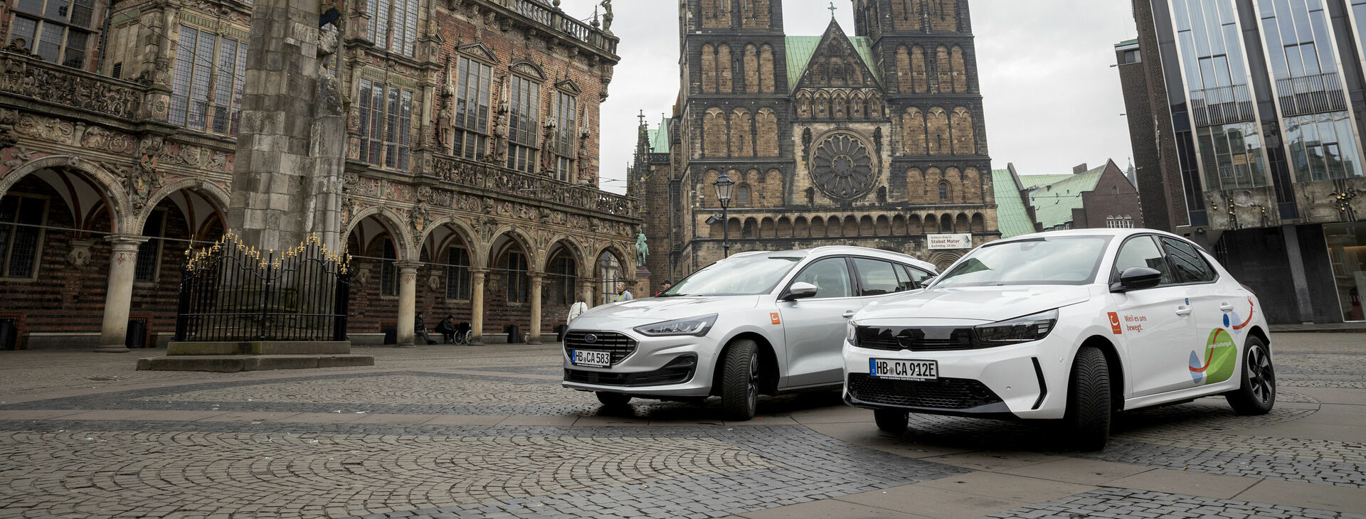 Zwei CarSharing-Autos stehen auf dem Bremer Marktplatz vor dem Rathaus