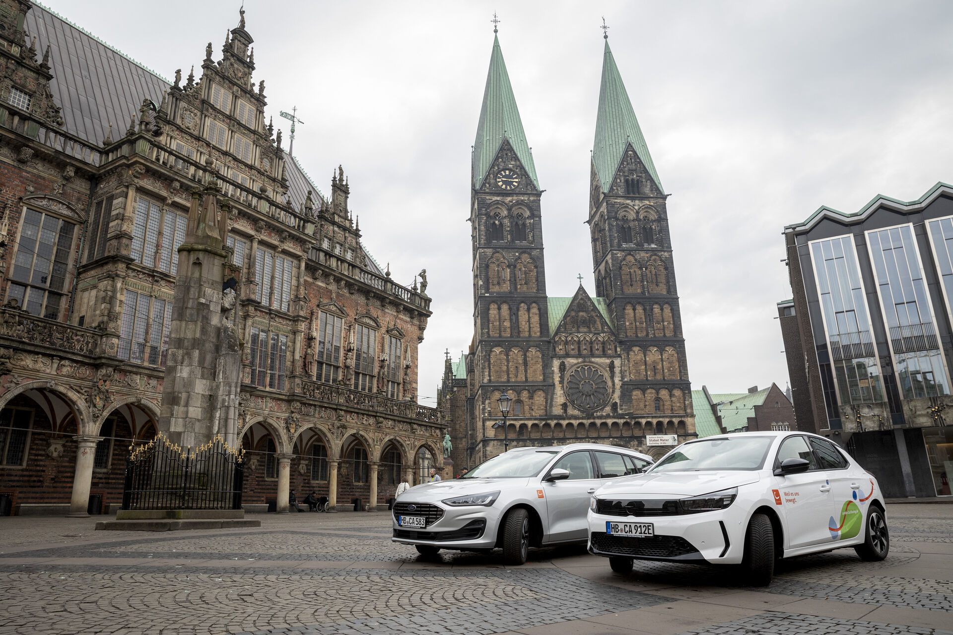 Zwei CarSharing-Autos stehen auf dem Bremer Marktplatz vor dem Rathaus
