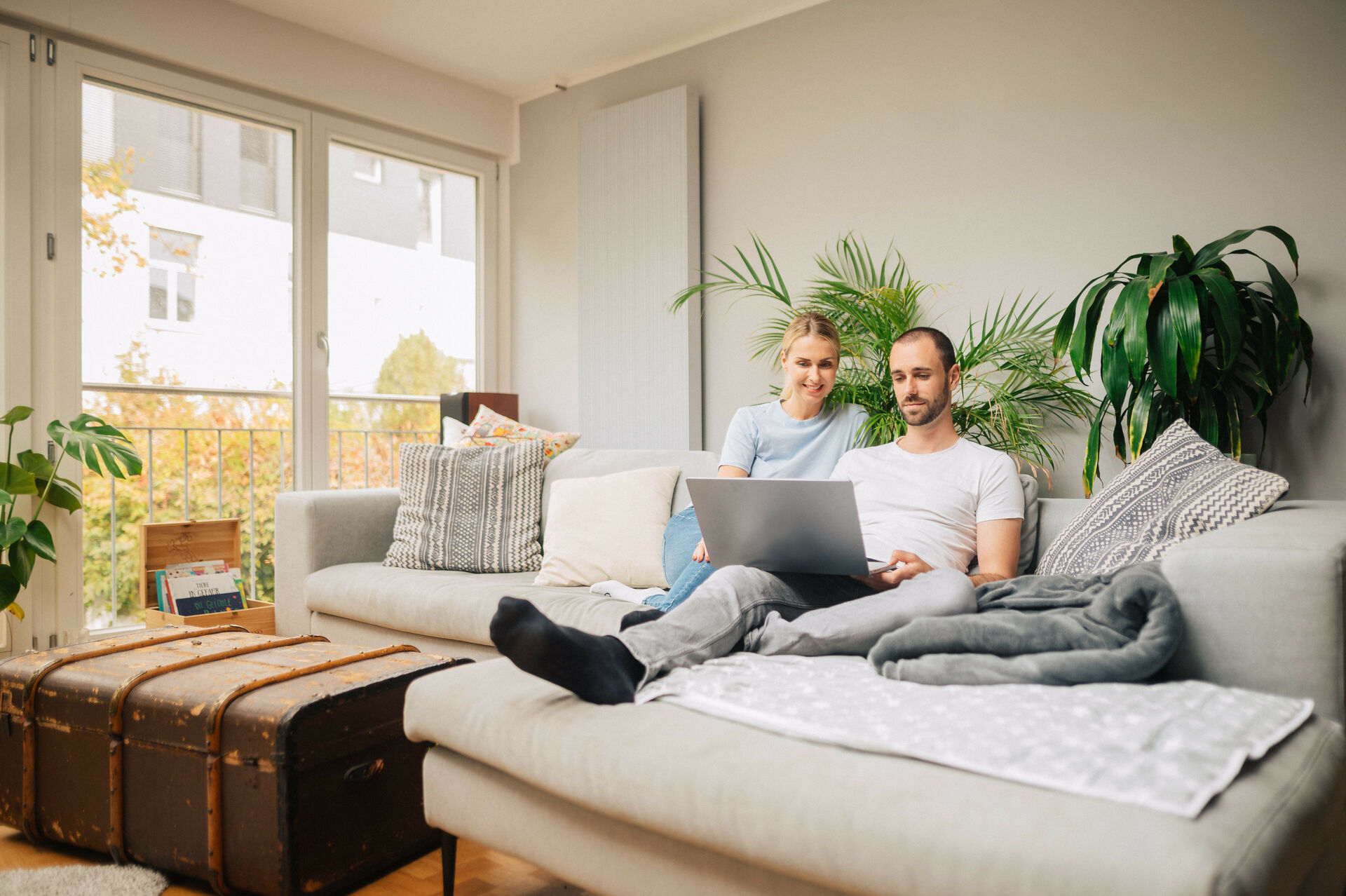 Frau und Mann sitzen mit einem Laptop auf einem Sofa