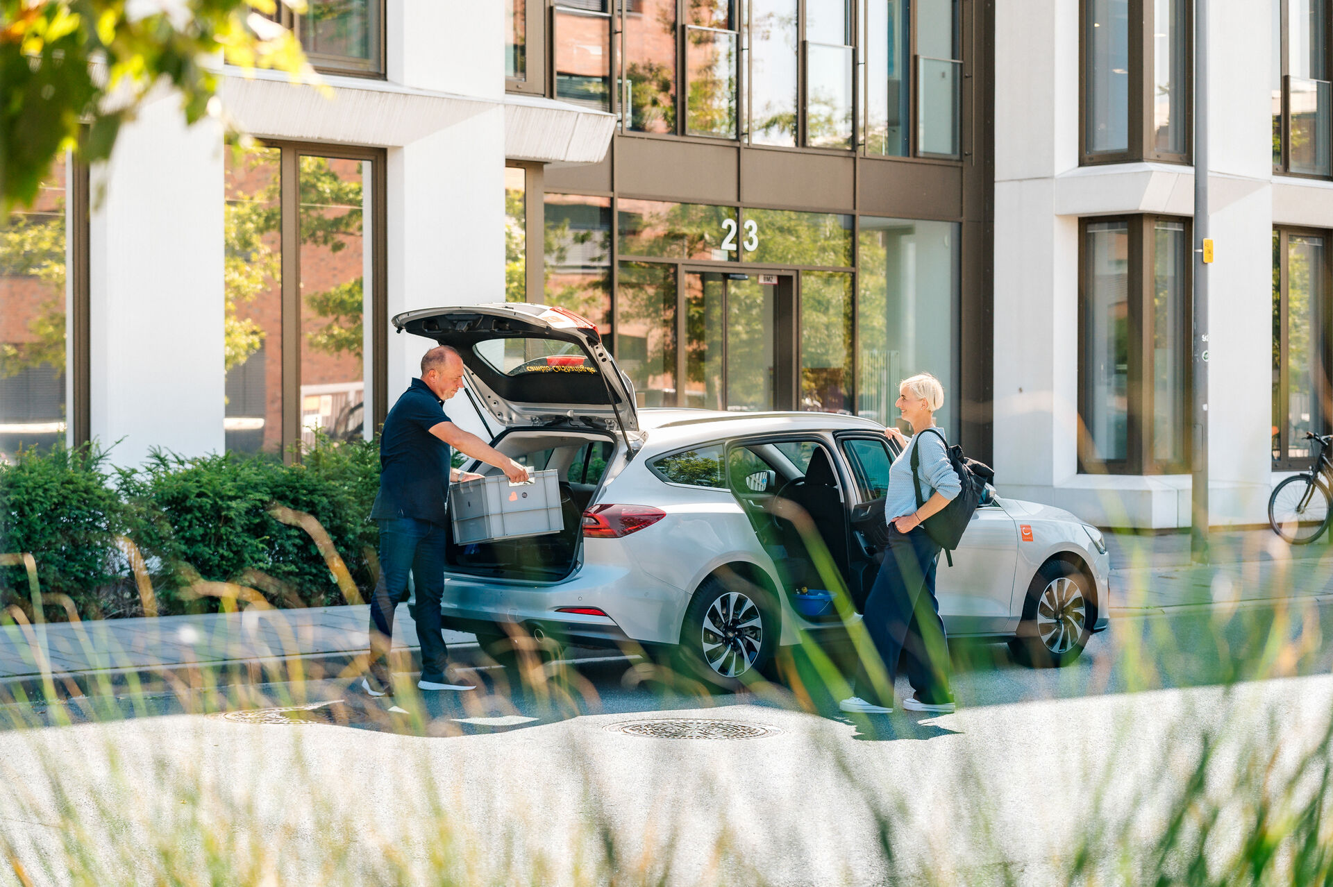 Zwei Personen laden etwas aus einem CarSharing-Auto aus.