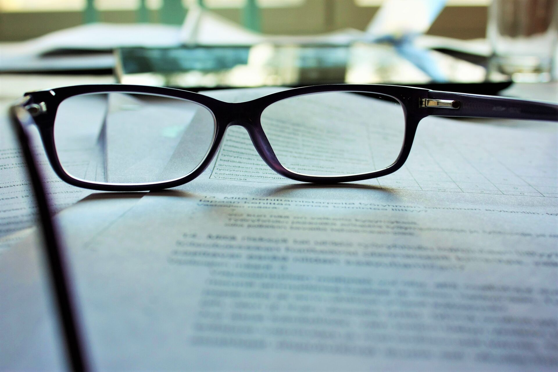 Lesebrille liegt auf bedrucktem Blatt Papier