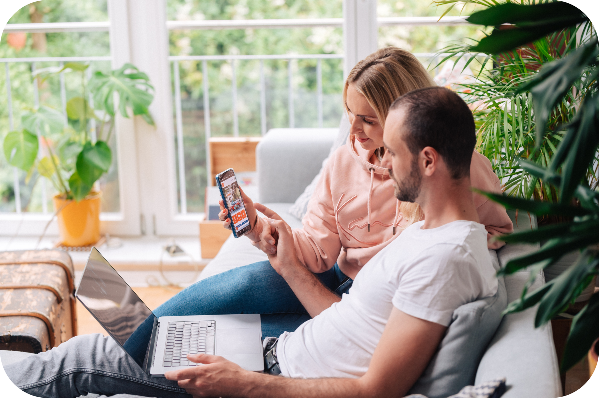 Mann und Frau sitzen auf einem Sofa und nutzen die Cambio App über das Smartphone