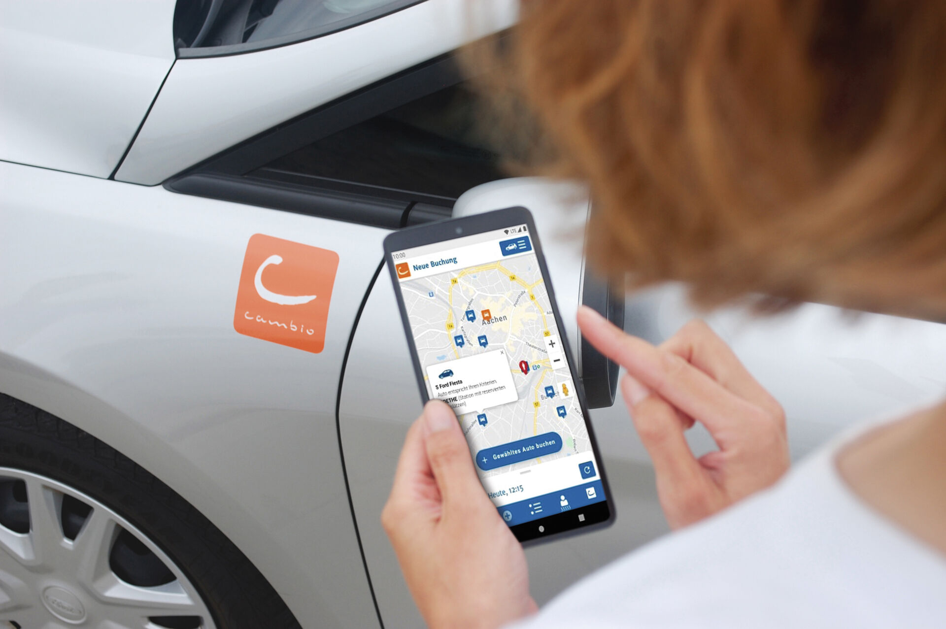Blick über die Schulter einer Person auf das Handydisplay, darauf ist die cambio-App geöffnet.